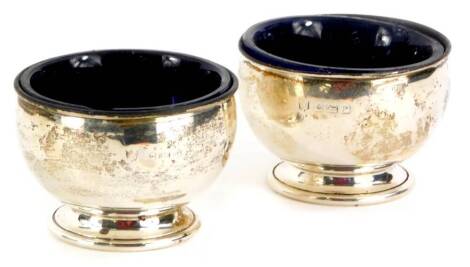 A pair of George V silver salts, of plain form, with blue glass liners, Birmingham 1914, 4cm high, weighable silver 1½oz.