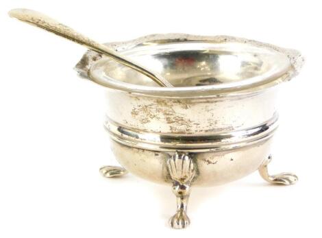 An Edwardian silver open salt, on lion paw feet, with glass liner, Birmingham 1906, 0.85oz, with a silver plated spoon.