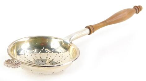 An Elizabeth II silver tea strainer, with turned wooden handle, London 1970, 18cm long, 1oz gross.