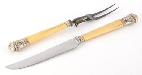 An early 20thC ivory handled carving set, comprising carving knife and fork, each with cream pommels, (2).