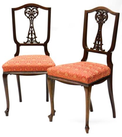 A pair of Edwardian mahogany salon chairs, each with a pierced carved splat, a padded seat on cabriole legs.