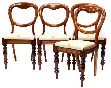 A set of four Victorian mahogany balloon back dining chairs, each with a padded seat and turned tapering legs.