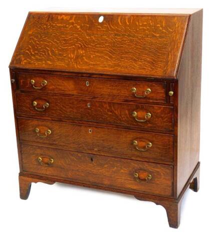 An early 19thC oak bureau, the mahogany crossbanded fall enclosing a fitted interior, above four graduated drawers, each with drop brass handles, on bracket feet, 110cm high, 95cm wide, 50cm deep.