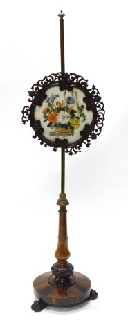 A William IV rosewood polescreen, with a part brass and turned pole, the banner with a pierced border inset with flowers and a bird, made in feather collage, on a circular platform base with paw feet, 150cm high.