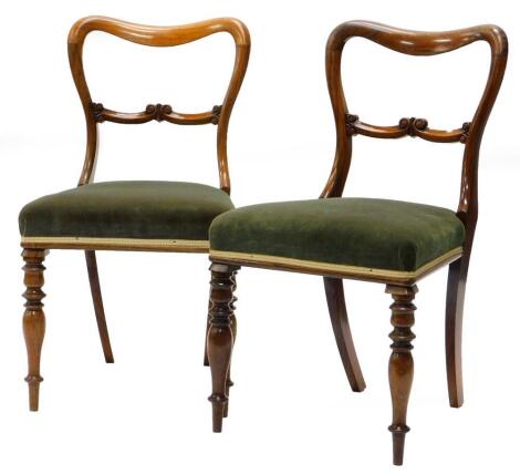 A pair of early Victorian rosewood balloon back chairs, each with a green padded seat on turned tapering legs.