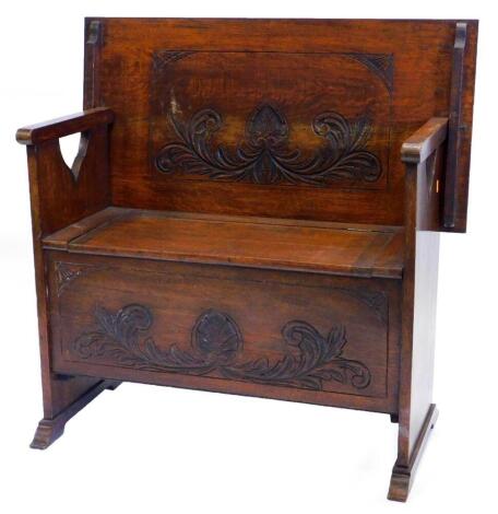 An early 20thC carved oak monk's bench, with a rectangular top with a moulded edge, on pierced end supports, the base with a hinged lid, and leaf and shell carve frieze, 92cm wide.