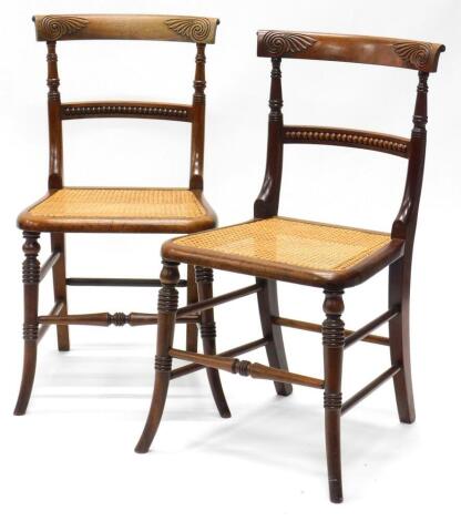 A pair of Victorian mahogany bedroom chairs, each with a leaf carved back, part turned supports and cane seat, with ring turned splayed legs.