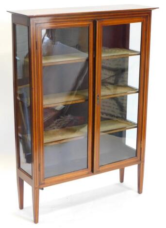 An Edwardian mahogany and boxwood strung display cabinet, with a moulded cornice, of two glazed doors enclosing fabric lined shelves, flanked by glazed sides, on square tapering legs, 137cm high, 97cm wide.