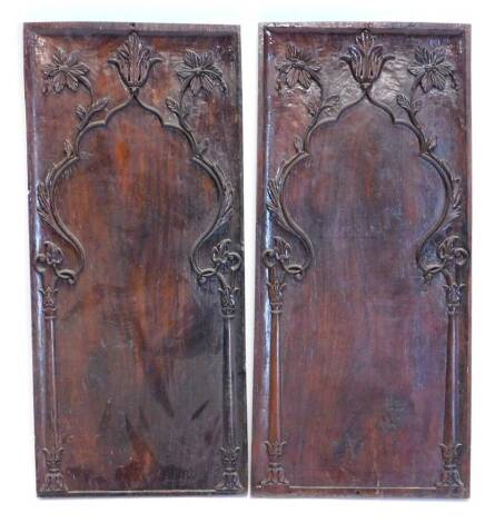 A pair of carved walnut panels, each decorated with flowers, leaves etc., 96cm x 42cm.