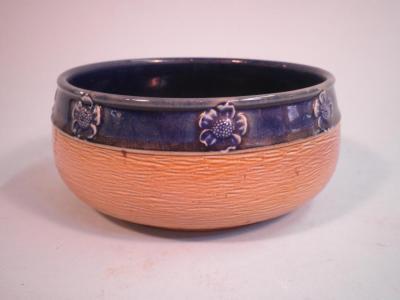 A Royal Doulton stoneware bowl decorated with a blue band and moulded with flower heads