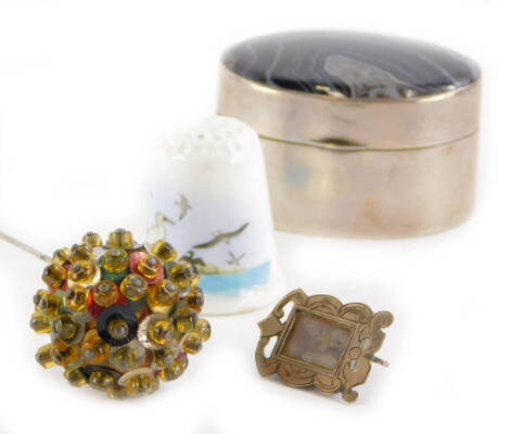 A collection of items, to include a continental white metal oval box inset with an agate, a hat pin applied with sequins, a Poole commemorative thimble, and a small white metal photograph frame. (4)