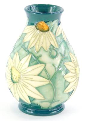 A Moorcroft pottery baluster vase, decorated with white flowers, with pale green leaves, on a green ground, impressed mark to underside, 14cm high.