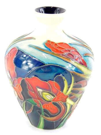 A Moorcroft pottery vase, decorated with a band of iris', on a blue and cream ground, 10cm high.