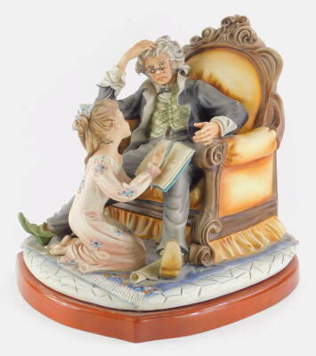 A large Capodimonte porcelain figure group, modelled in the form of a gentleman seated on a throne type chair, with a young girl reading on a mahogany plinth, 39cm x 30cm.