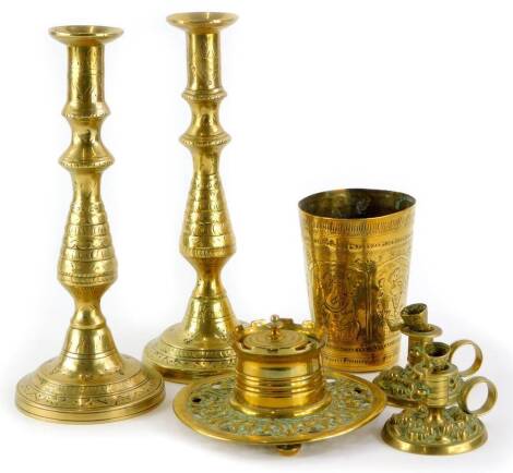 A circular brass inkwell, 23cm diameter, a pair of cast brass chamber sticks, a pair of engraved candlesticks and a beaker (6).