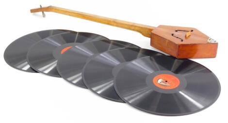 A single string pine and fruitwood guitar type musical instrument, with fret cut sound holes, 79cm long, and five records.