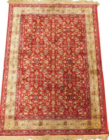 A Kashmir rug, with an all over meandering design of scrolls, flowerheads, leaves, etc., one wide and two narrow borders, 169cm x 117cm.