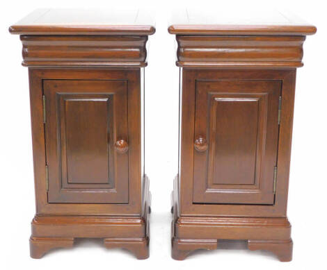 A pair of continental mahogany bedside cabinets, each with a moulded top above a baize lined drawer and a panel door with turned wooden handle, on bracket feet, 71cm high, 39cm wide, 41cm deep.