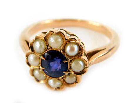 A sapphire and seed pearl daisy ring, the central oval cut sapphire surrounded by seed pearls, in raised and curved setting, yellow metal, unmarked, ring size L, 3.2g all in.