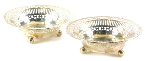 A pair of George V silver bon bon dishes, each with a pierced border on ball feet, Birmingham 1912, stamped Ollivant and Botsford, Manchester, 7½oz, 16cm diameter.