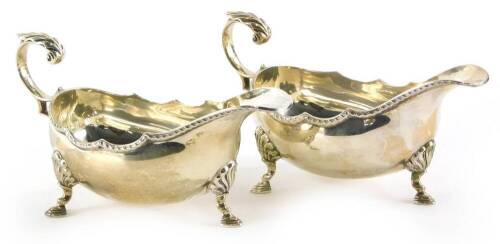 A pair of Elizabeth II silver sauce boats, each with a shaped border, a scroll cast handle and three feet, Birmingham 1978, 7¼oz.