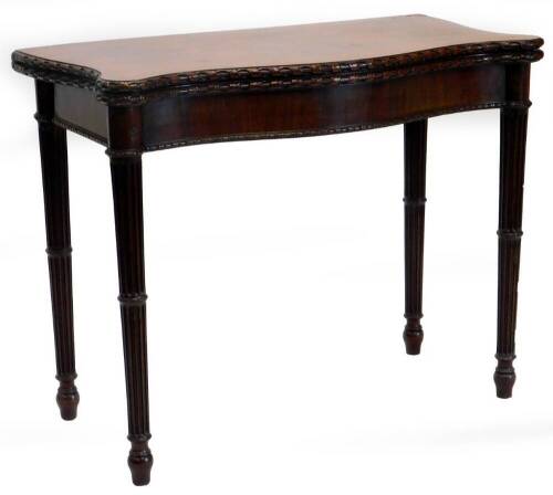 A George III mahogany card table, the serpentine shaped top with a carved border, enclosing a baize lined interior, above a plain frieze on turned and reeded tapering legs, 74.5cm high, 93cm wide, 47cm deep.