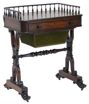 An early Victorian rosewood writing table or desk, the top with a three quarter gallery, with pierced supports above a frieze drawer, fitted with a hinged and ratcheted writing slope, etc., on carved X shaped moulded end supports, with scroll carved feet,