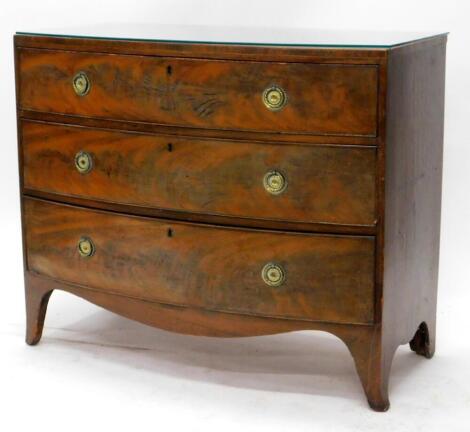 An early 19thC mahogany bow fronted chest of drawers, the caddy top with a crossbanded boxwood strung border, above three graduated drawers, each with circular ring handles on bracket feet, 87cm high, 105cm wide, 52cm deep.