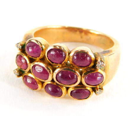 A ruby and diamond dress ring, with three rows of cabochon cut rubies and four tiny diamonds, on a yellow metal band, unmarked, ring size K, 6.8g all in.