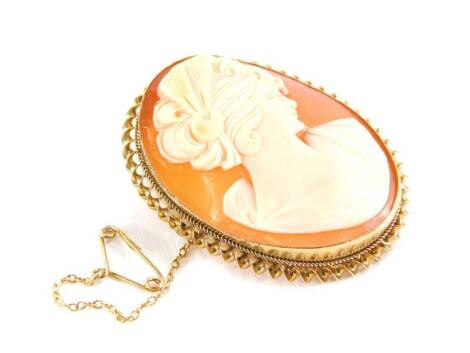 A 9ct gold framed shell cameo brooch, the oval cameo depicting a lady in dress with elaborate hair, in rub over frame with rope twist borders, 4cm high, with steel back pin and safety chain, Birmingham 1970, 10.8g all in.