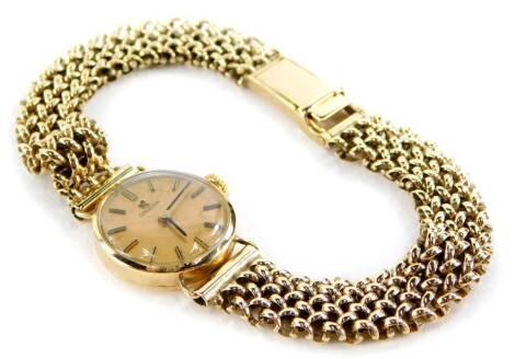 A 9ct gold Omega wristwatch, the small circular dial on gold coloured finished with black handles, on a woven design bracelet, the watch head 2cm wide with bezel, the watch strap approximately 20cm long, 22.1g all in.