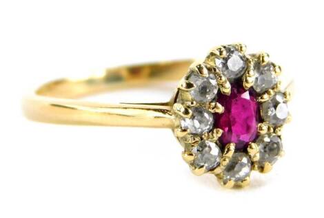 A ruby and diamond cluster ring, with over cut ruby in claw setting, surrounded by round brilliant cut diamonds, on a yellow metal band stamped 18ct, ring size R, 3.5g all in.