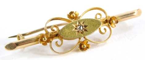 A Victorian bar brooch, set with a tiny diamond in an illusion setting, surrounded by floral scroll bordering, yellow metal stamped 15ct, 4cm wide, 2g all in.