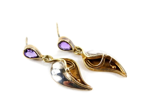 A pair of Art Nouveau style amethyst and silver drop earrings, the tear drop cut amethyst studs with a bi-colour lily drop, stamped to rear 925, 4cm high, lacking backs, 7.4g all in.