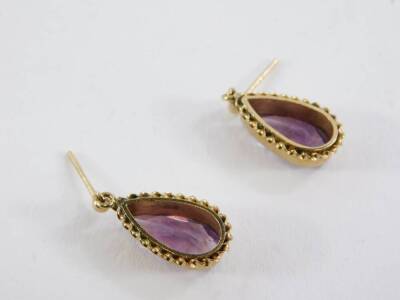 A pair of 9ct gold amethyst drop earrings, the teardrop cut amethyst in a raised setting with rope twist border, lacking backs, 1.5cm high, 3.8g all. - 2