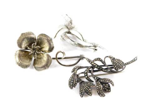 Three floral brooches, to include a marcasite lily brooch, stamped silver, a four leaf flower brooch stamped sterling and brushed lily brooch stamped sterling. (3)