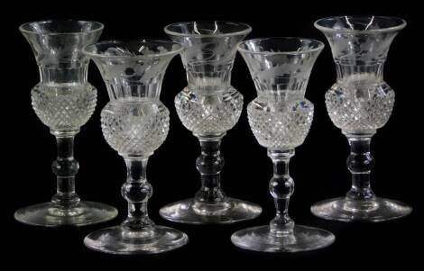 A set of five cut glass thistle shaped whisky or spirit glasses, each engraved with a band of thistles, and with cut glass and plain knop, on a domed foot, 9.5cm high. Auctioneer announce. A total of five glasses as per image and not six.