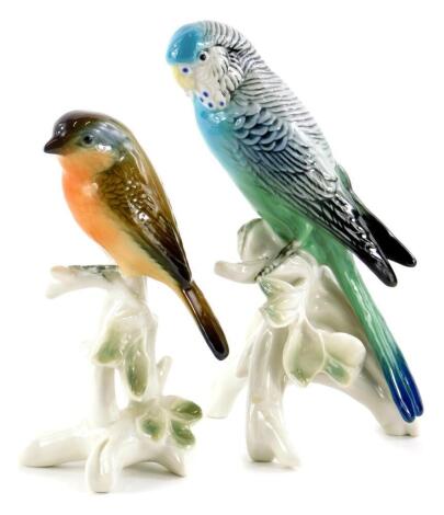 Two Karl Ens porcelain birds, a robin and a budgerigar on a leafy base, the budgerigar 17cm high.