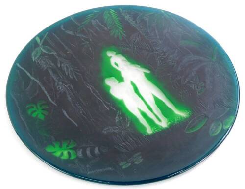 A green acid etched and engraved plaque, depicting a male, female and a child in a jungle setting, in the manner of Webb, unmarked, 27cm diameter.