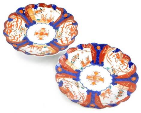 A pair of Japanese Imari porcelain chargers, each with a shaped border and decorated in blue, red and green, with flowers, leaves, etc., 31cm diameter.