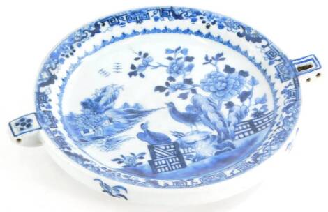 A late 18th/early 19thC Chinese blue and white porcelain warming plate, decorated with birds, a fence, buildings, etc., (AF), 26cm wide.