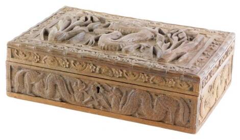 An oriental carved hardwood cigarette or cigar box, the hinged lid decorated with dragon, flanked by two flowers, within a border of flower heads, etc., 30cm x 20cm.