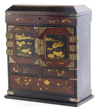 An early 20thC Japanese lacquered jewellery cabinet, with a hinged lid above two doors, each with silver plated mounts, decorated with a river landscape enclosing four small drawers, above two short and one long drawer on a plinth, 29cm high, 25cm wide.