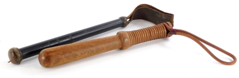 A turned hardwood truncheon, with leather strap, and an ebonised and turned wooden truncheon or kosh, with leather end and strap. (2)