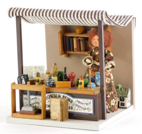 A Graham and Pearly Jackson model group, depicting Brown and Sons general stores, with a lady behind a counter, various bottles, a rocking horse, books, etc., signed to underside, 17cm high, 15cm wide.