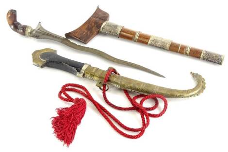 A Malayan Kris, with hardwood and silver coloured metal, scabbard, elaborately shaped blade and wooden handle, 46cm long, and an Eastern dagger, with a brass and silver coloured metal curved scabbard, stained wooden handle, etc., the blade stamped 5, 45cm