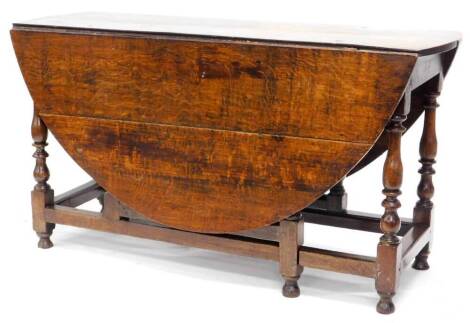 An 18thC oak drop leaf table, with an oval top on turned legs with stretchers, 74.5cm high, 137cm wide.