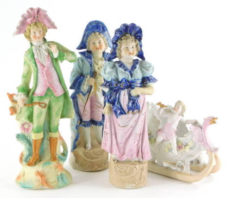 A collection of four late 19thC German bisque porcelain figurines, a pair of figures in blue and pink of a gentleman and lady, a figure of a gentleman wearing 18thC costume, and a centrepiece modelled with a putto riding a troika or sleigh. (4)