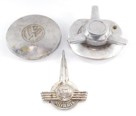 A VW hub cap, three spoke propeller cap, and a Morris Minor car badge. (3)