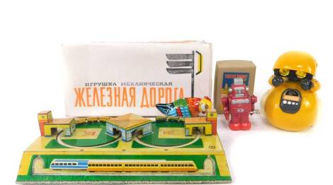 A Russian tinplate double loop train track, boxed, lacking key., a Japanese wind-up robot., a tinplate chicken., and a Shoulder Remo-Carn Rover. (4)